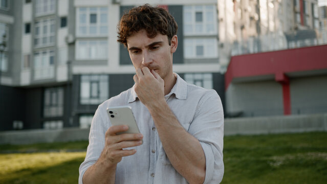 Pensive Caucasian man using mobile phone smartphone thinking thoughtful guy ponder looking around gps navigator maps online male businessman city business outdoors solution browsing employer problem - Powered by Adobe