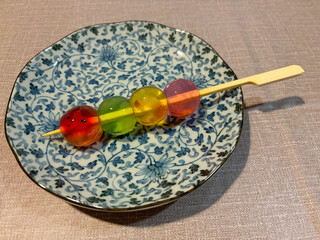 Colorful jelly in the shape of small round balls, served on a skewer stick.