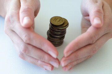 Hands gently enclosing stack of coins, protection of savings, financial security