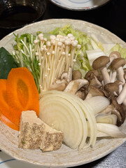 Closeup of a plate of raw vegetables and mushrooms, suitable to be used in Asian cuisine such as...