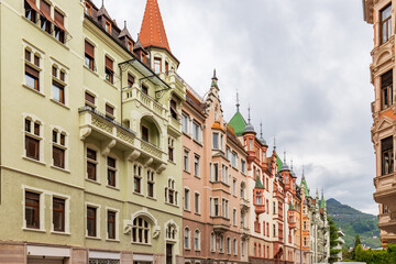 Obraz premium A row of charming, colorful European buildings with unique architecture and decorative roofs, against a cloudy sky.