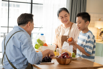 Asian grandparents support and help grandson cooking breakfast in the kitchen. Grandmother and...