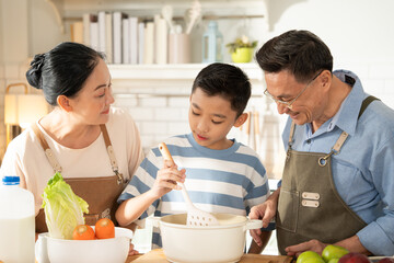Asian grandparents support and help grandson cooking breakfast in the kitchen. Grandmother and...