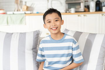 Portrait of Asian boy sitting on couch in the living room looking at camera