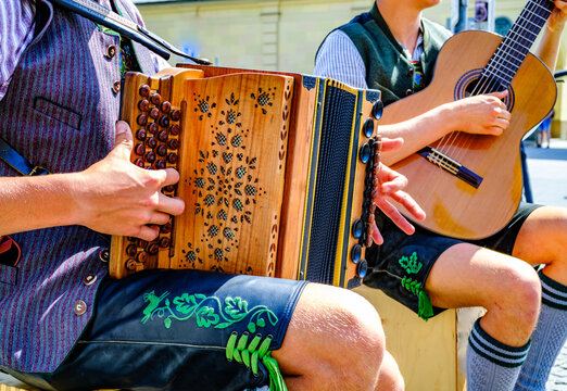Musicians performing traditional folk music in colorful attire outdoors on a sunny day in a lively urban square