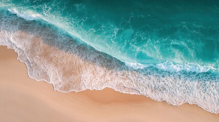 Beautiful aerial view of turquoise ocean waves crashing onto sandy beach coastline during daytime.