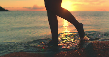 Woman walks sunset beach in Thailand, . Close up barefoot legs walking. Slim female feet ocean...