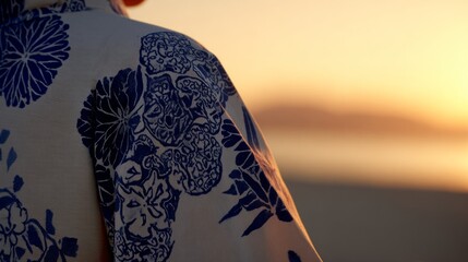 A detailed kimono sleeve with traditional dance patterns, set against a softly blurred golden sunset.
