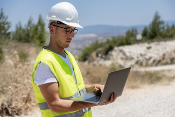 Engineer inspecting wind turbines with a laptop outdoors