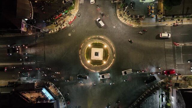 Yogyakarta, Indonesia - 7 June 2023: A vibrant aerial night shot of the iconic Tugu Yogyakarta monument, glowing at the center of a bustling roundabout with streams of city traffic