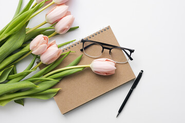 Fresh pink tulips and notebook or diary on white background. Springtime.