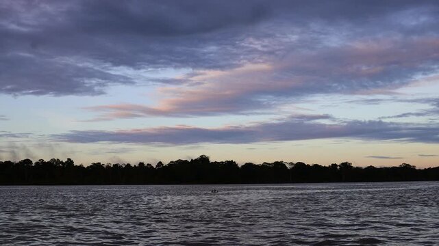 Amazon River at sunset view. Calm water reflecting orange sky, dense rainforest coastline. Peaceful, natural landscape, tropical jungle, South America, scenic beauty, golden hour