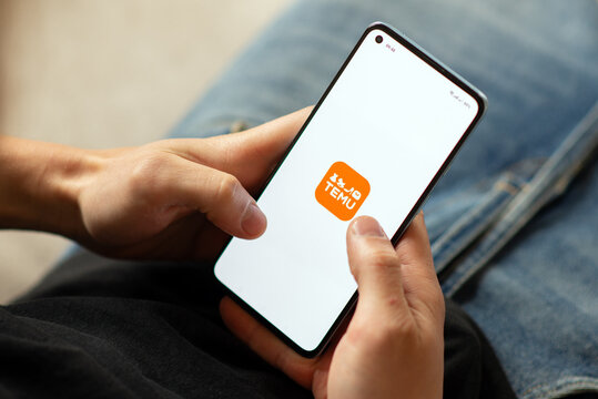 Kyiv, Ukraine - July 16, 2025:  Close-up of a person holding a smartphone with the TEMU shopping app open on the screen.   online shopping in a relaxed home setting 