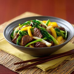 Beef and vegetable stir fry in a dark bowl with chopsticks