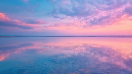 Beautiful wide panoramic view of a serene pink and purple sunset reflection on a calm lake surface.