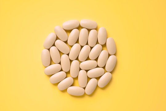 Pills arranged in a circular pattern on yellow background