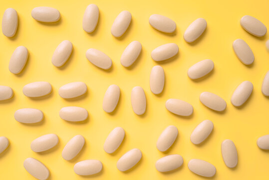 Pills scattered on a vibrant yellow background