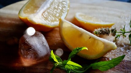 Fresh lemon slices with ice cubes and mint leaves on a wooden surface. Refreshing composition for summer drinks, cocktails, or natural ingredients themes.