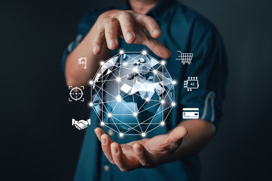 businessman hold a glowing digital globe with interconnected icons representing AI, finance, e-commerce, targeting, handshake, and global connectivity, modern digital transformation and technology. - Powered by Adobe