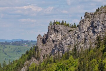 A rocky mountain with some trees sits beneath a blue sky with clouds in Zakopane - Lesser Poland - Poland
