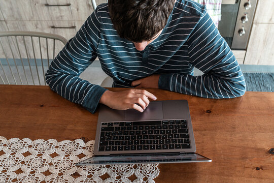 Over the shoulder view of a person typing and using a laptop at home