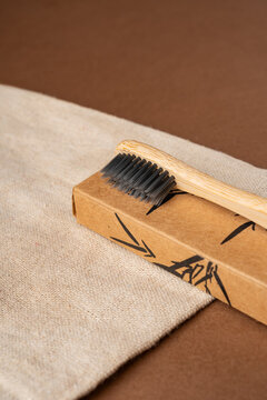 Bamboo toothbrush on cardboard box with beige fabric
