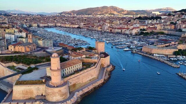 orbiting drone shot of Marseille old port, France, flying over historic fort and ships in the marina in French port of Marseille at sunset, fortress of Marseille 
