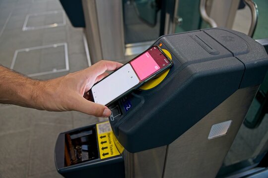 Man using NFC contactless payment near electronic validator, paying for public transport with mobile phone
