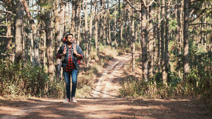 A couple is hiking along a forest trail on a beautiful day, enjoying nature and their outdoor...