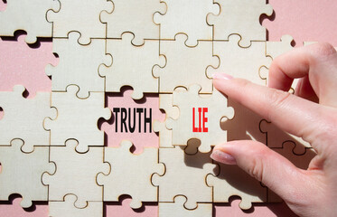 Truth or Lie symbol. Concept word Truth or Lie on wooden puzzle. Businessman hand. Beautiful pink...