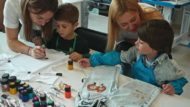 Young teachers at art school teach young children how to decorate and create unique denim clothes. They teach them how to craft these clothes in way that creates unique style.