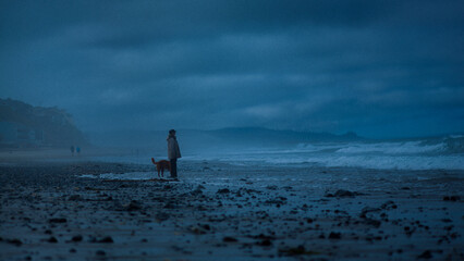 Person walks dog on foggy morning at the beach in Oregon