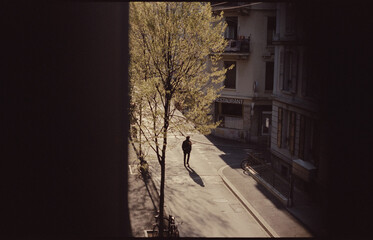 Dark shadow of a figure walking across the street in the early morning sun