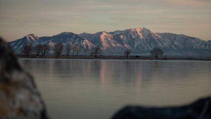 Sun kissed mountains with snow and a peaceful lake