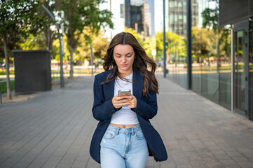 Businesswoman walking and using smartphone in urban setting