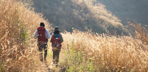 A couple is hiking along a forest trail on a beautiful day, enjoying nature and their outdoor adventure perfect for themes of travel, hiking, and togetherness. © NewSaetiew