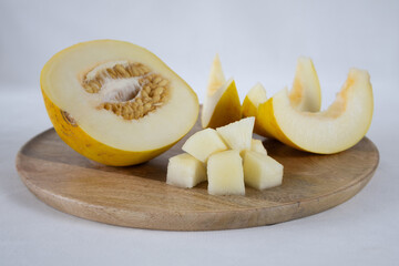 Sliced melon on a wooden tray on a light background