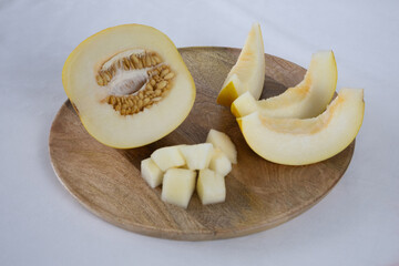 Sliced melon on a wooden tray on a light background