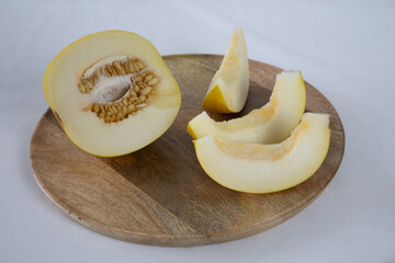 Sliced melon on a wooden tray on a light background