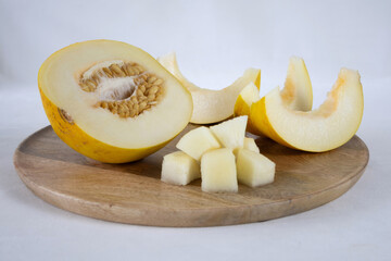 Sliced melon on a wooden tray on a light background