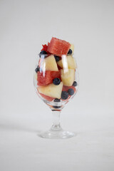 Watermelon and melon cubes, and blueberry in a glass on a light background