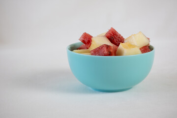 Watermelon and melon cubes in a blue bowl on a light background