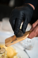 Shaving black truffle with wooden slicer – close-up