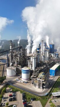 Imagem a&eacute;rea mostra ind&uacute;stria de papel e celulose com caldeiras e chamin&eacute;s expelindo gases. A composi&ccedil;&atilde;o destaca elementos industriais e ambientais em contraste