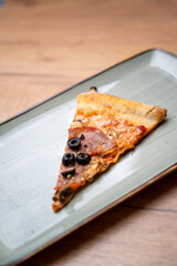 Pizza slice with olives and ham – top view