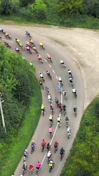 Aerial view A peloton of cyclists enters a sharp turn in the countryside. Overcoming the marathon distance on a bicycle by a group of cyclists.