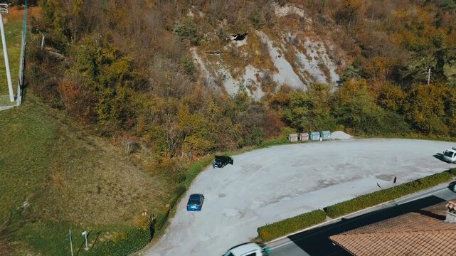Drone shot of Lake Idro with hillside homes, autumn trees, green meadows, and blue water
