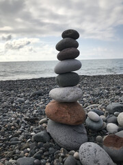 Stacked Stones on Beach Shoreline with Ocean in Background Under Overcast Sky