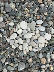 High-angle close-up showcasing an assortment of smooth pebble stones arranged closely together. The stones display a range of gray tones and soft textures, suitable for backgrounds