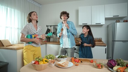 Caucasian skilled father, mother and asian daughter making breakfast while dancing together....
